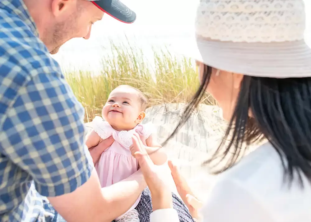 Are baby looks to daddy and smiles on the beach Portland ​Family Photographer Robert Knapp - Book Today!​Family Photographer Robert Knapp in Portland - Book Today!