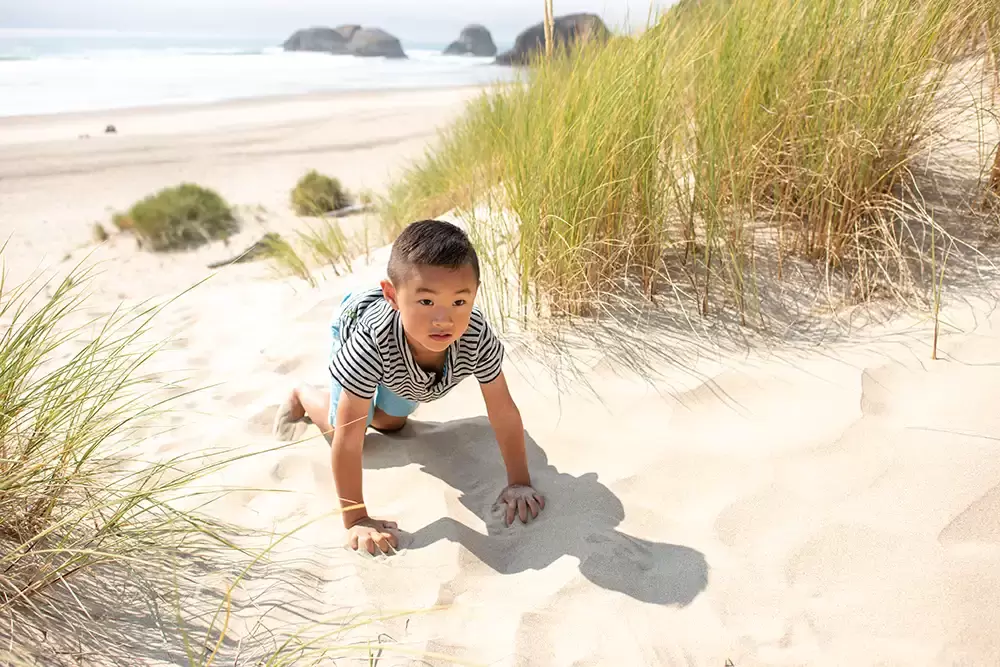A little boy climbs a dune. The ocean is in the background. Portland ​Family Photographer Robert Knapp - Book Today! ​Family Photographer Robert Knapp in Portland - Book Today!