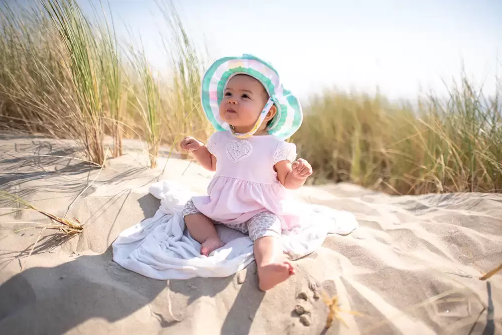 baby sits in the sand before some sea grasses Portland ​Family Photographer Robert Knapp - Book Today! ​Family Photographer Robert Knapp in Portland - Book Today!