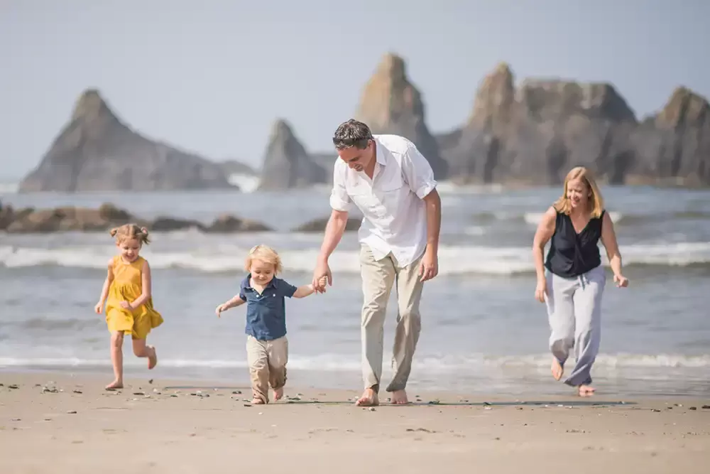 families love to have photos like this on the beach! Dad and son hold hands and run, mother and  daughter run along either side. The ocean in the background   Family Pictures Beach Theme with Portland Family Photographer Robert Knapp