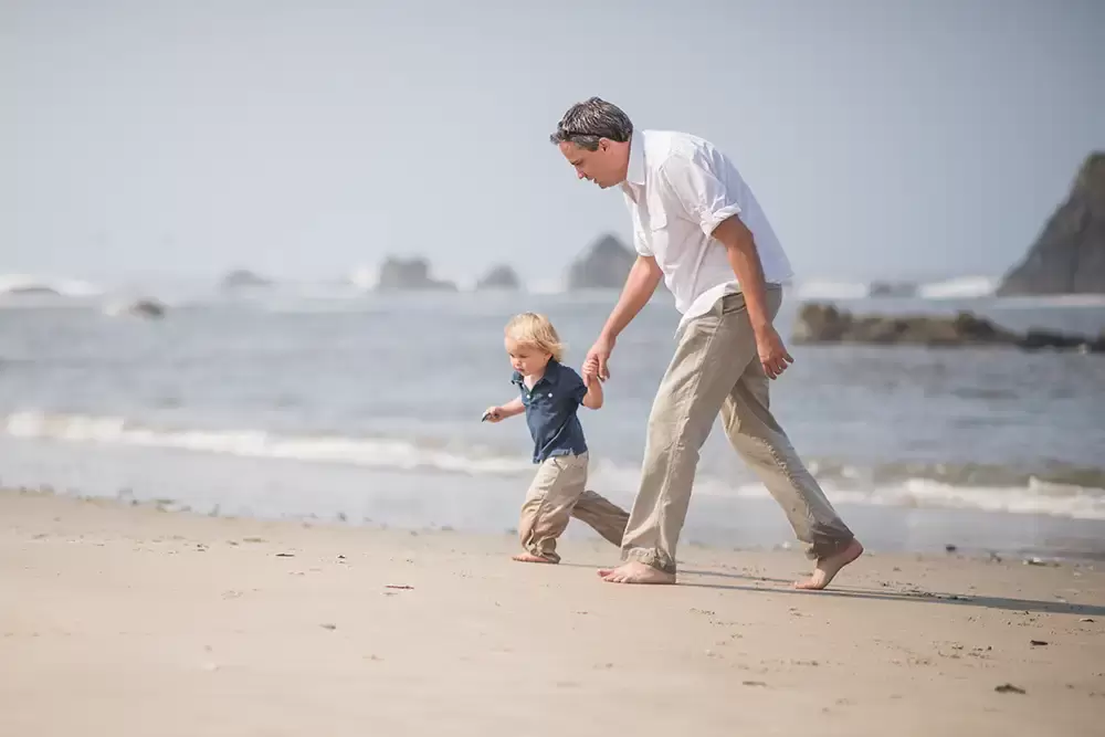 dad and son run in the sand on the beach together   Family Pictures Beach Theme with Portland Family Photographer Robert Knapp