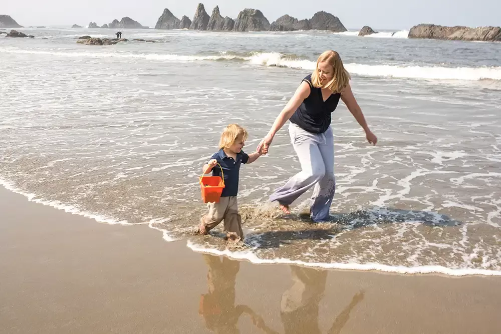 a mother and son walk in the waves together   Family Pictures Beach Theme with Portland Family Photographer Robert Knapp