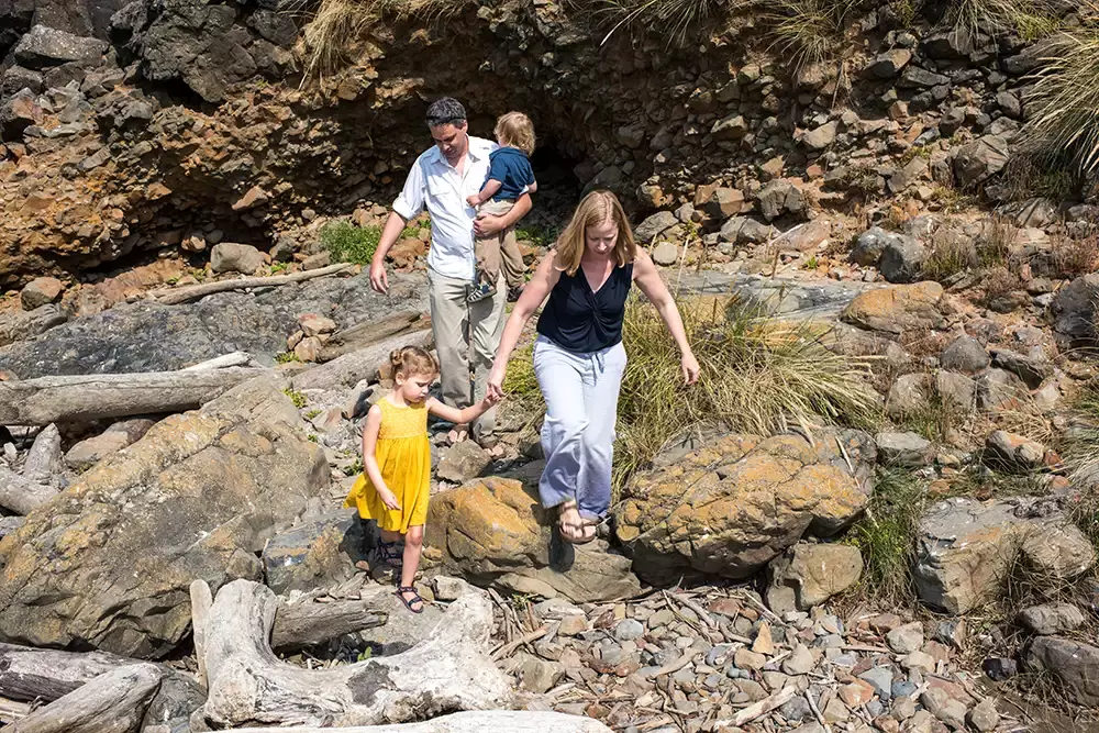 a family walks down a rocky bank together   Family Pictures Beach Theme with Portland Family Photographer Robert Knapp