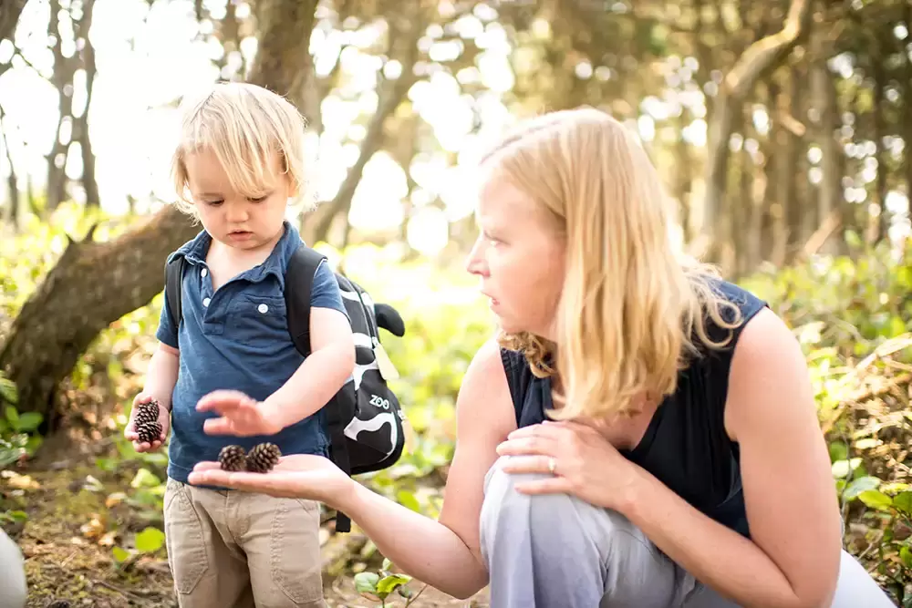 a mother hands a little boy a pine cone   Family Pictures Beach Theme with Portland Family Photographer Robert Knapp