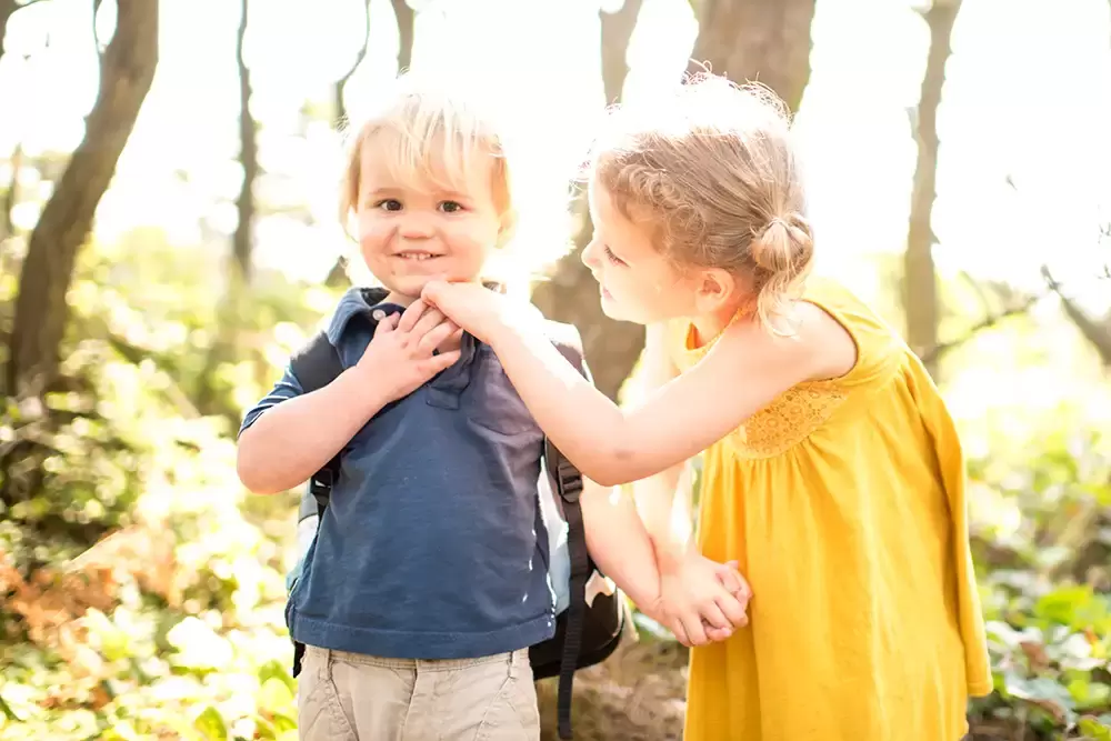 brother and sister hold hands in the forest. The little girl tries to get a smile from the little brother   Family Pictures Beach Theme with Portland Family Photographer Robert Knapp