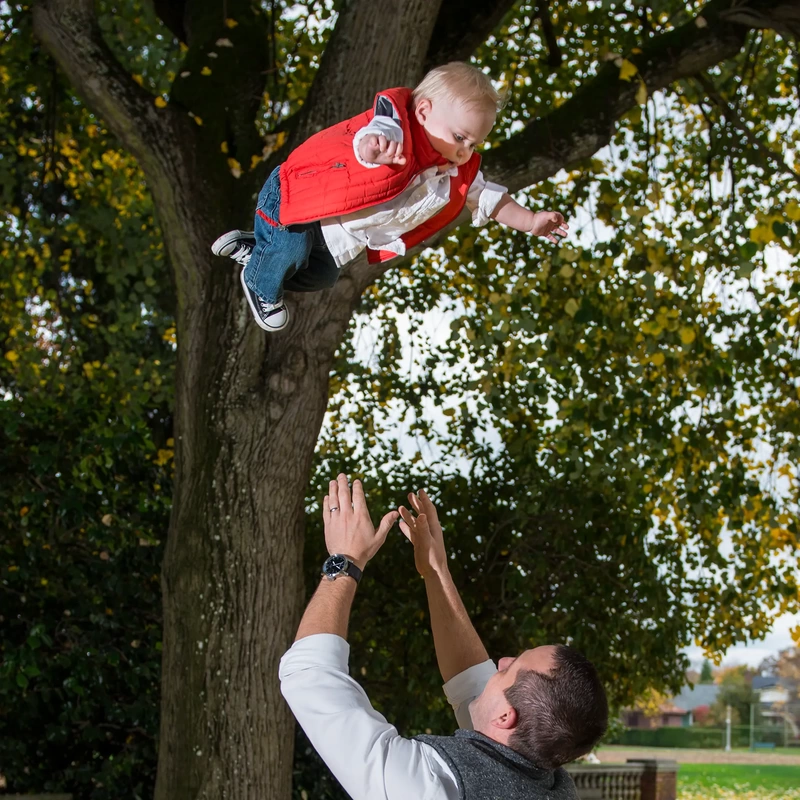 father tosses baby in the air for a photo Family Photography by Robert Knapp in Portland City Parks