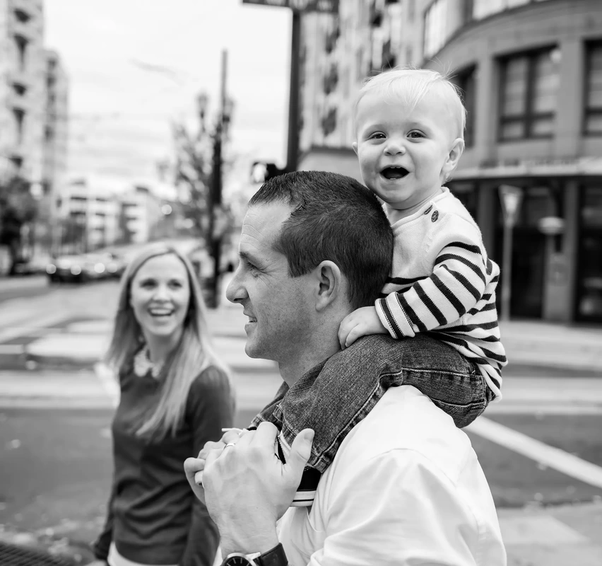baby sits on a father shoulders and laughs to the camera Family Photography by Robert Knapp in Portland City Parks