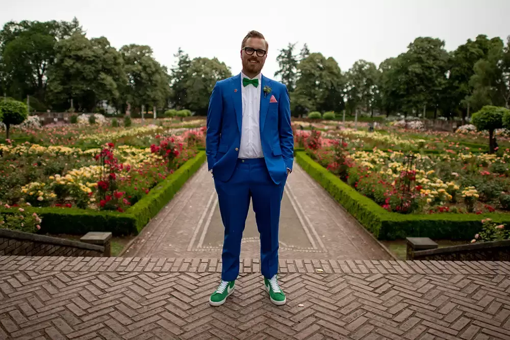 Polaris Hall
Portland Oregon Wedding Venue
Photographer Robert Knapp at Modern Art Photograph the groom stands in the Rose Garden. The pass is made of brick roses flank. His sides and his head intersects the tree line.  he wears a bowtie a blue suit and some sneakers