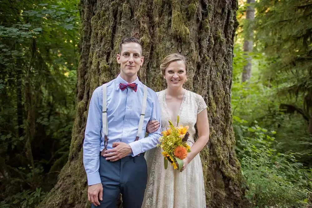 just after the ceremony the bride and groom stand in front of a very old tree and smile toward the camera at Silver Falls Weddings with Modern Art Photograph