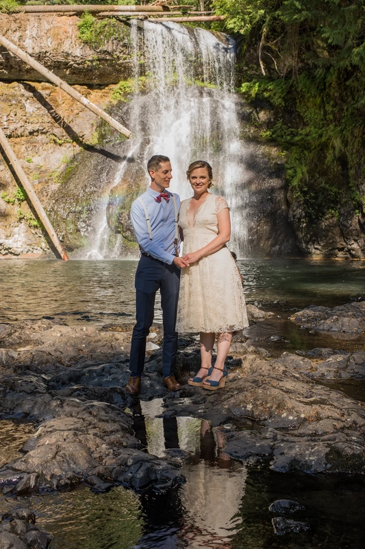 Silver Falls Weddings with Modern Art Photograph A bride and groom stand in front of a waterfall. 