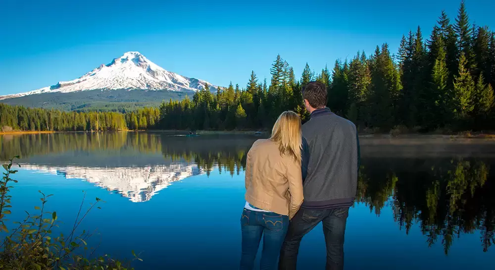 a couple is turned away from the camera facing a mountain and trees reflecting in the water of a lake Unforgettable Moment - Mountain Engagement Photos 
with
​ Photojournalist Photographer Robert Knapp