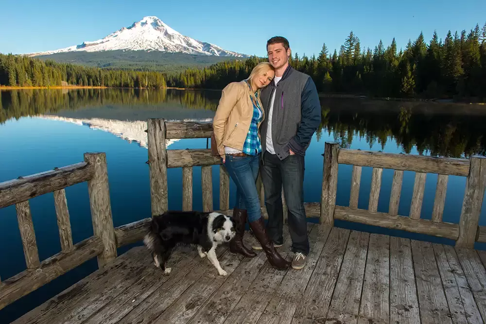 a couple stands with their dog in front of a lake and a snow capped mountain Unforgettable Moment - Mountain Engagement Photos 
with
​ Photojournalist Photographer Robert Knapp