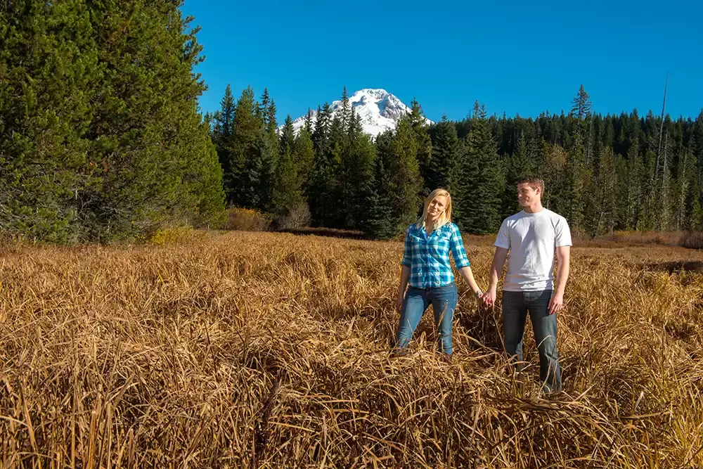 a snow capped mountain raises above a couple holding hands in a field Unforgettable Moment - Mountain Engagement Photos 
with
​ Photojournalist Photographer Robert Knapp
