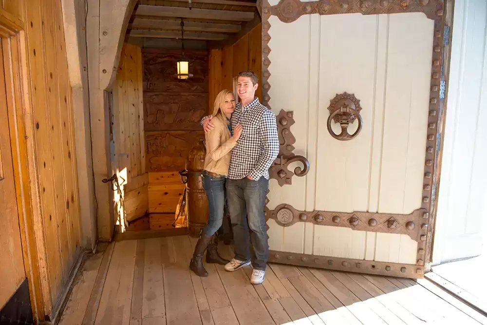 mountain engagement photos posing in front of a massive door to the lodge Unforgettable Moment - Mountain Engagement Photos 
with
​ Photojournalist Photographer Robert Knapp