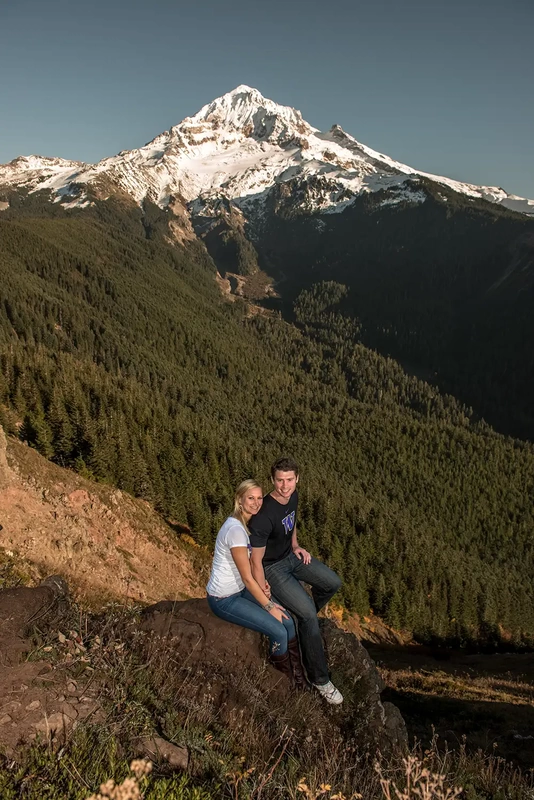 mountain engagement photos of a couple sitting on a ledge over a ravine. In the background a mountain peak takes the entire frame, Unforgettable Moment - Mountain Engagement Photos 
with
​ Photojournalist Photographer Robert Knapp