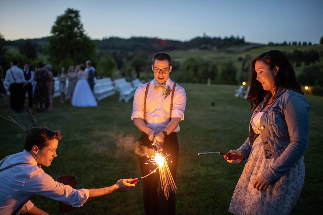 Vineyard Wedding Oregon with a groomsman lighting all the sparklers at one time