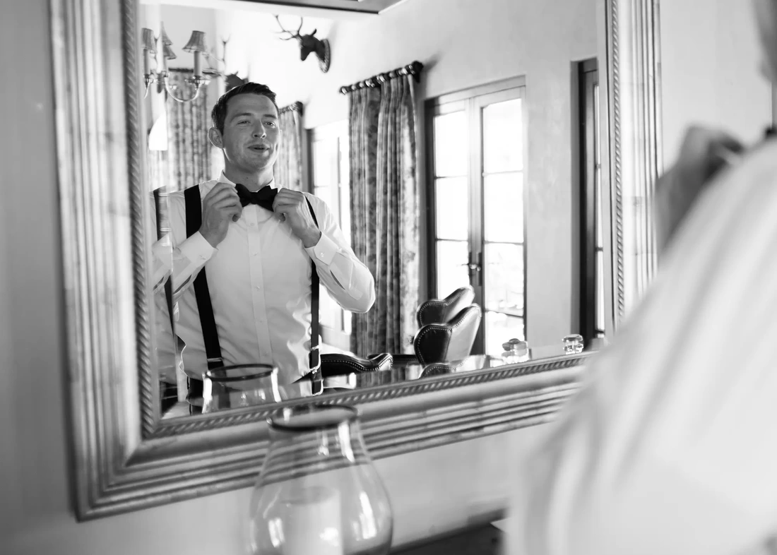Wedding Photographers in Bend Oregon  Modern Art Photograph's photography from a Ranch at the Canyons Wedding in the mirror the groom straightens his bow tie Wedding Photographers in Bend Oregon  Modern Art Photograph's photography from a  ​Ranch at the Canyons Wedding