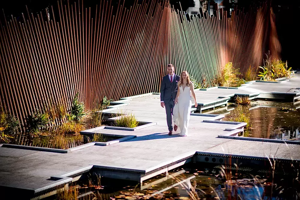 Wedding Photographers in Portland  at the EcoTrust Robert Knapp Photographer Tanner Springs park, the deck is interesting in its design. The bride and groom walk across the top of the oddly shape deck. The look put together well. 