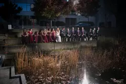 Wedding Photographers in Portland  at the EcoTrust Robert Knapp Photographer A dramatic photo of the wedding party. They sit in the park together. A beam of light reflects down from a tall building to the group creating the look of flash photography. The group is lit, the background is very dark. the lighting effect is interesting to look at