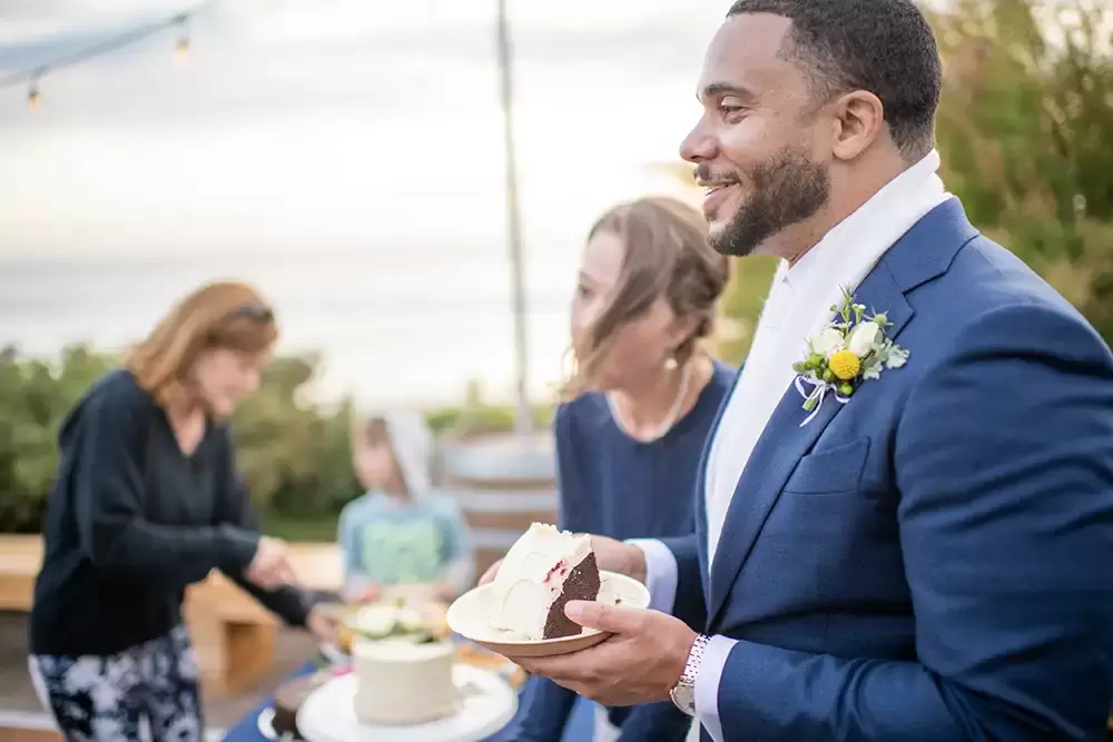 groom smiles a warm smile with cake in hand Wedding Photographers Near Me