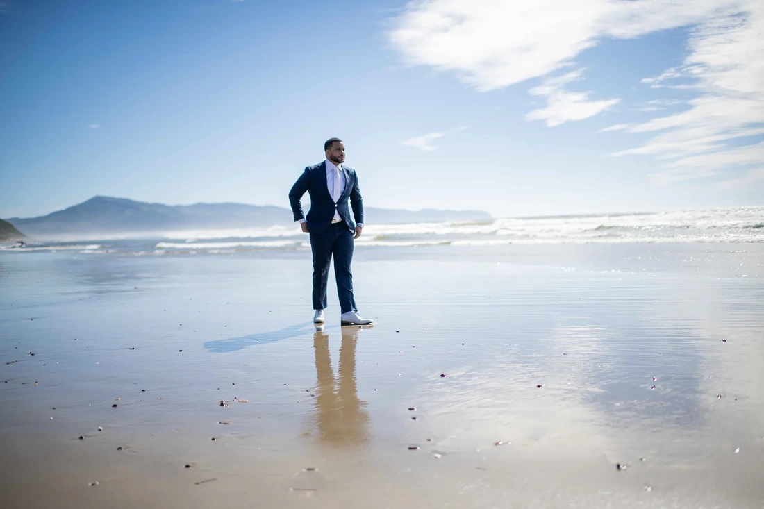 Photographers for weddings Near Me | Modern Art Photograph Wedding Photography from Oceanside, OregonThe groom stands on the beach. The sand is wet reflecting him and the blue sky mirroring the horizon. Wedding Photographers Near Me 