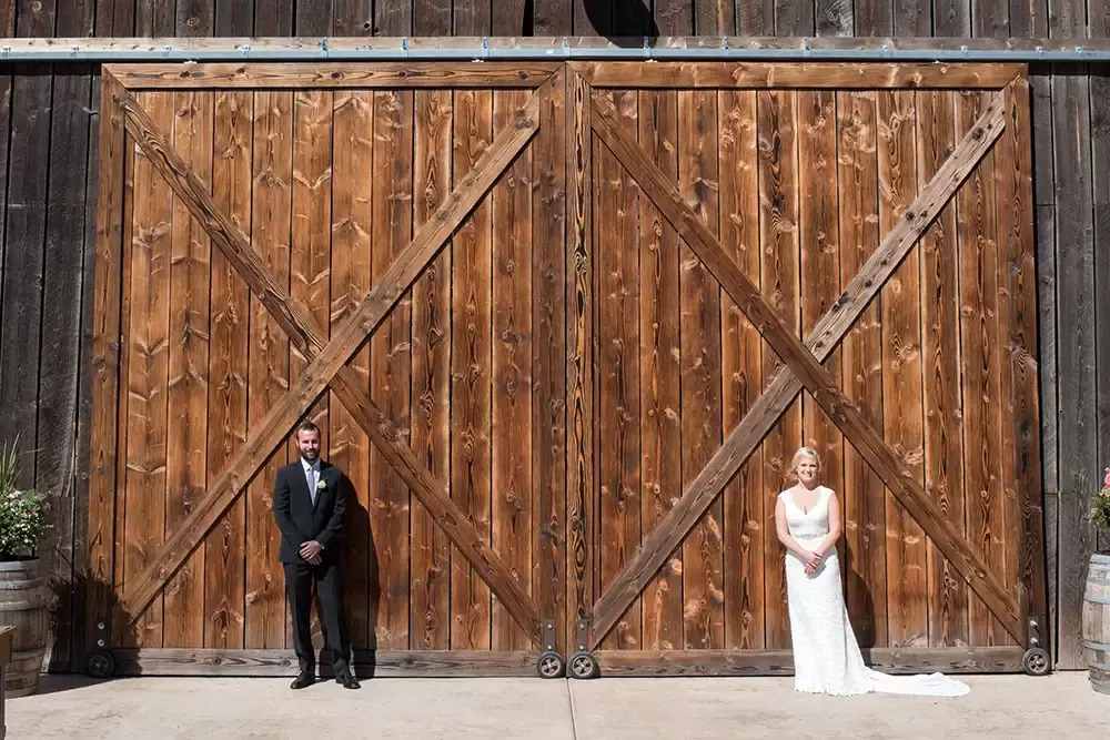 Tin Roof Weddings Barn Weddings Venues Near Me from Photographer Robert Knapp Bride and groom stand in front of barn doors