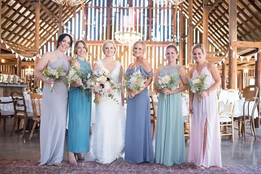 Tin Roof Weddings Barn Weddings Venues Near Me from Photographer Robert Knapp Bride and bridesmaid all hold their flowers and looked at the camera. They are all smiling. They are all very happy.