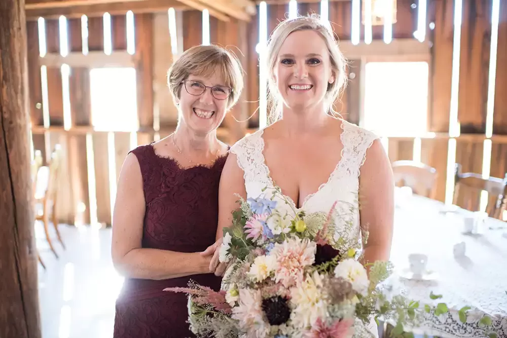 Tin Roof Weddings Barn Weddings Venues Near Me from Photographer Robert Knapp Mother of the bride and the bride looking to the camera smiling the background is the inside of the barn sunshine is shining through all the boards just very bright