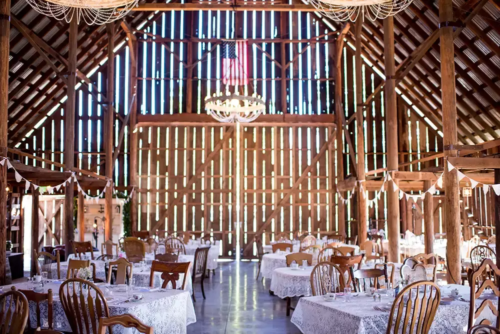 Tin Roof Weddings Barn Weddings Venues Near Me from Photographer Robert Knapp Inside the venue of the barn before everyone arrives the barn doors are closed. Sunlight shines through the cracks. All the tables are set, and the scene is ready for a party.