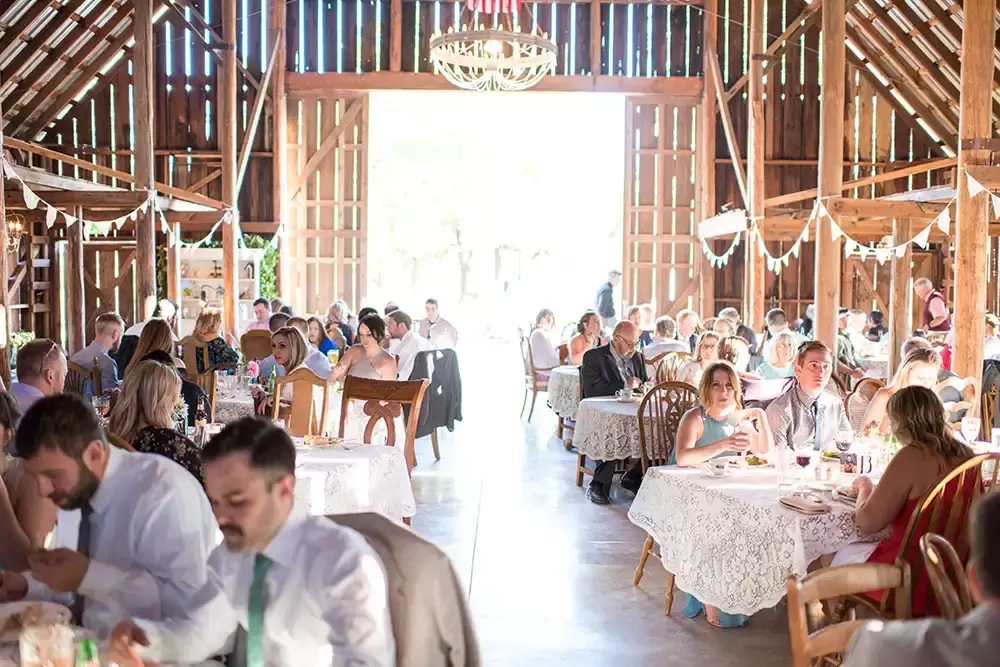 Tin Roof Weddings Barn Weddings Venues Near Me from Photographer Robert Knapp The reception has begun. All the guests are seated inside the barn. The scene is full.