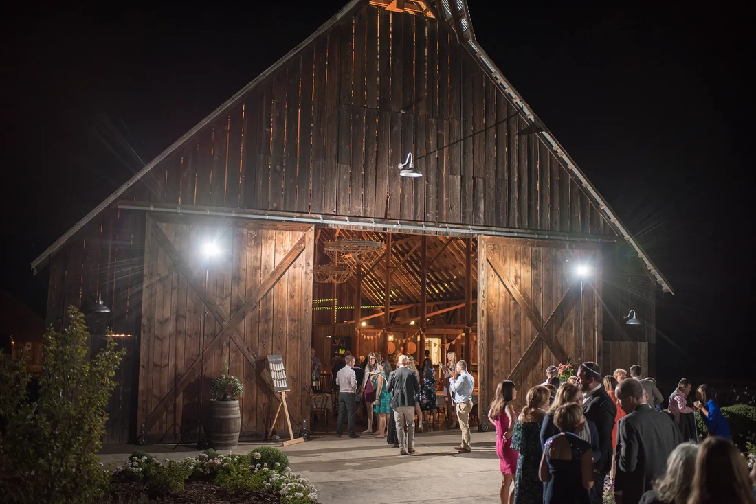 Tin Roof Weddings Barn Weddings Venues Near Me from Photographer Robert Knapp the evening light of the reception guests and the barn are lit against the dark sky.